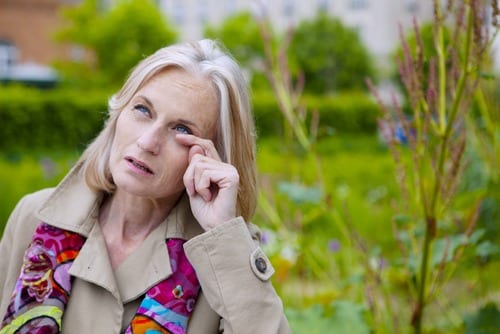 woman wiping eye from spring allergy symptoms
