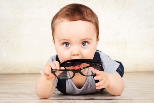 infant holding pair of glasses
