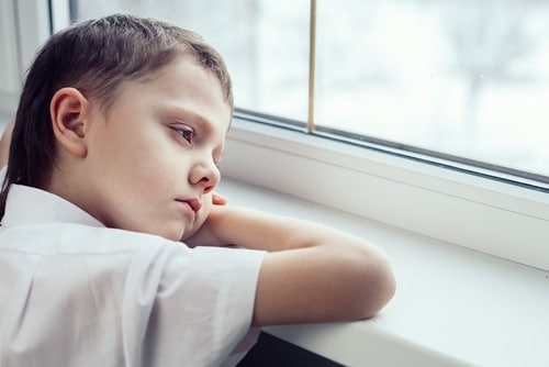 sad boy with learning related vision problems looking out window