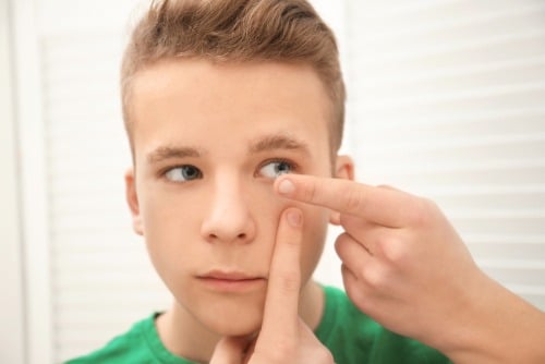 Young boy putting in contact lens for kids